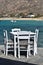Traditional Greek taverna table and chairs with the sea and beach as a backdrop.