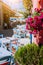 Traditional Greek vivid colored tavern with purple flowers on the narrow Mediterranean street on hot summer day