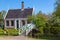 Traditional green dutch house with little wooden bridge against blue sky in the Zaanse Schans village, Netherlands. Famous tourism