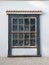 Traditional guillotine window in historic colonial house. Front view of closed old sash window on white concrete facade.