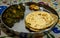 Traditional homemade Cuisine Palak Paneer or spinach cottage cheese with wheat chapati and jaggery in steel plate