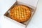 Traditional homemade rustic baked pie with seasonal fruit or meat filling in cardboard box  on white. Fast food to go.