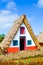 Traditional house in Santana, Madeira island, Portugal. Small, wooden, triangular houses with thatched roof and colorful facade.