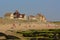 Traditional houses on the north sea of in Audresselles, France, with beach with people and mossy rock coast in front