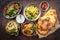 Traditional Indian curries and biryani with mango chutney and pita bread on rustic korai bowls