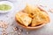 Traditional indian food samosa in wooden  plate with mint chutney on a gray concrete background. side view