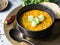 Traditional Indian lentil dal soup. Hot and spicy lentil soup with fresh cucumber slices in a black stone bowl and pita on a coppe