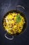 Traditional Indian vegetarian biryani with nuts and raisins in a rustic korai