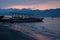 Traditional indonesian fishing boats in pink sunrise on shore with blue mountains in haze, colorful sky, calm sea with yellow.