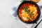 Traditional israel dish. Eggs with tomatoes. Dish Shakshouka in a pan on light table. Top view, copy space