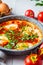 Traditional Israeli shakshuka in gray frying pan. Fried eggs in tomato sauce, close-up