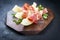 Traditional Italian antipasti with prosciutto di Parma and honeydew melon slices on a wooden design board