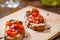 Traditional Italian bruschetta with cherry tomatoes, cheese, basil and balsamic vinegar on wooden board.