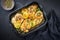 Traditional Italian deep-fried chicken piccata with capper and lemon slices in a rustic old roasting pan