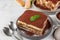 Traditional italian dessert tiramisu on plates. Homemade tiramisu cake portions with fresh mint and spoons