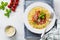 Traditional Italian dish fettuccine pasta with bolognese sauce, basil and parmesan cheese in a white plate on a light wooden backg