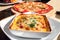 Traditional Italian Lasagna made with Minced Beef Bolognese Sauce topped with Basil Leaves served on a White Plate