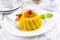 Traditional Italian mango pudding with glaceed cherry on a classic design plate