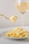 Traditional Italian pasta - Fetuccini Alfredo on a white table with golden appliances