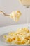 Traditional Italian pasta - Fetuccini Alfredo on a white table with golden appliances