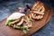 Traditional Italian Porchetta arrotolata pork meat sandwich with pita bread and rocket salad on a modern design wooden board