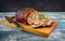 Traditional Italian Porchetta arrotolata pork meat sliced and as piece with herbs