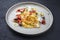 Traditional Italian ravioli pasta offered with parmesan cheese, fried tomatoes and olives on a modern Nordic design plate