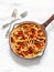 Traditional italian roman pasta - bucatini with amatricana tomato sauce in a cooking pan on a light background, top view