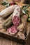 Traditional Italian salami with black ripe olives on an old wooden cutting board