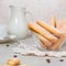 Traditional italian savoiardi or ladyfingers biscuits in a glass bowl and pieces of cookies and sugar on the table