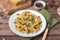 Traditional Italian Sicilian fusilli pasta with bread crumbs and green beans, sprinkled with cheese in a white plate on a wooden