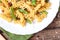 Traditional Italian Sicilian fusilli pasta with bread crumbs and green beans, sprinkled with cheese in a white plate on a wooden