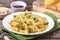 Traditional Italian Sicilian fusilli pasta with bread crumbs and green beans, sprinkled with cheese in a white plate on a wooden