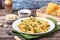 Traditional Italian Sicilian fusilli pasta with bread crumbs and green beans, sprinkled with cheese in a white plate on a wooden