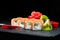 Traditional Japanese cuisine. Selective focus on sweet sushi rolls with salmon, cream cheese, rice and kiwi on dark background, n