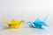 Traditional Japanese origami cranes made of blue and yellow paper on a white background. Pair of colorful paper birds