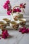 Traditional Japanese tea set filled with green tea and fresh red cheery blossom against white marble back