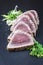 Traditional Japanese tuna tataki filets with sesame and leek slices on a design stone board