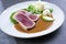 Traditional Japanese tuna tataki fillet with rice, wasabi ceam and chili sauce on a classic design plate