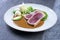 Traditional Japanese tuna tataki fillet with rice, wasabi cream and chili sauce on a classic design plate