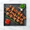 Traditional Kebab. Juicy chicken kebab with vegetables on a black stone plate. Barbecue. Top view.
