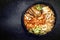 Traditional Korean kimchi jjigae with grilled pork belly and ramen in a pot with copy space left