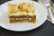 Traditional lasagne served on a white round plate, dark background. Side view.