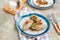 Traditional Lithuanian dish Zeppelin, boiled potato dumplings stuffed with minced pork, on a colored ceramic plate on a gray