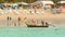 Traditional long wooden motor boat and tourists walk on a Kamala beach on low tide time with beach