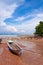 Traditional longtail boat on the sand beach at the low tide. Sea view with islands on horizon and clouds in the sky.