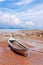 Traditional longtail boat on the sand beach at the low tide. Sea view with islands on horizon and clouds in the sky.