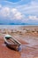 Traditional longtail boat on the sand beach at the low tide. Sea view with islands on horizon and clouds in the sky.