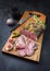 Traditional lunch meat with sliced cold cuts roast beef with gherkin and fig fruit on a modern design cutting board