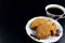 Traditional Malaysian cake called `kuih bahulu or baulu` in fish shape, in flowery plate with a cup of coffee over dark background